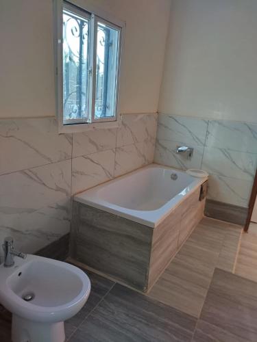 a bathroom with a tub and a toilet and a window at White House Residences in Tujering