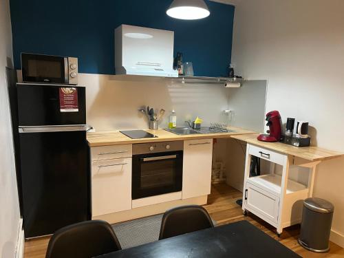 Elle comprend une petite cuisine équipée d'un réfrigérateur noir et d'une table. dans l'établissement Appartement centre St Genest Malifaux, à Saint-Genest-Malifaux
