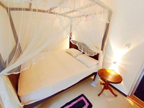 a bedroom with a canopy bed with a wooden chair at White King Guest in Unawatuna