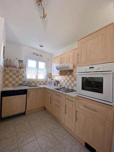 - une cuisine avec des placards en bois et un four micro-ondes blanc dans l'établissement Maison de vacances, à Bretignolles-sur-Mer
