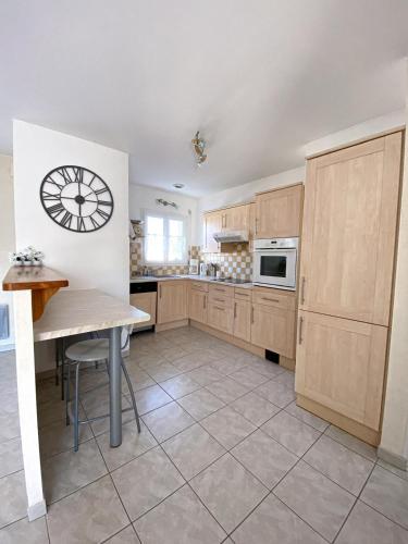 une cuisine avec une table et une horloge au mur dans l'établissement Maison de vacances, à Bretignolles-sur-Mer