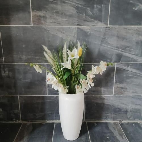 a white vase with white flowers in it at Le Quereau in Saint-Macoux
