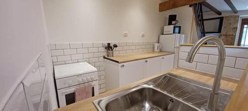a kitchen with a sink and a stove at Le Quereau in Saint-Macoux
