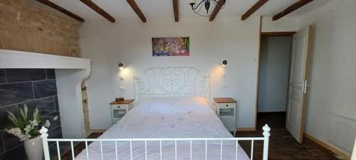 a bedroom with a white bed and a fireplace at Le Quereau in Saint-Macoux