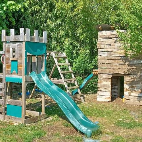 a playground with a slide next to a wooden structure at Le Quereau in Saint-Macoux