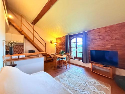 Villemur-sur-TarnにあるCocon paisible et confortable.のレンガの壁、リビングルーム(テレビ付)