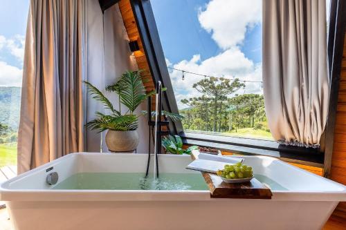 a bath tub in front of a large window at A Cabana mais aconchegante da Serra Catarinense in Urubici