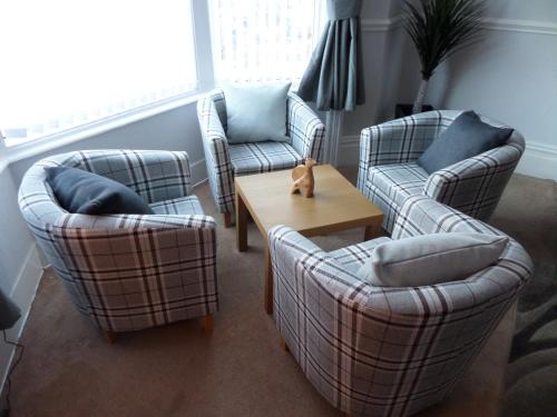 a living room with three chairs and a table at Nathans in Blackpool