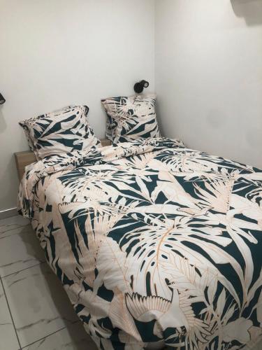 - un lit avec une couette et des oreillers en noir et blanc dans l'établissement Cozy and well located apartment, à Tremblay-en-France