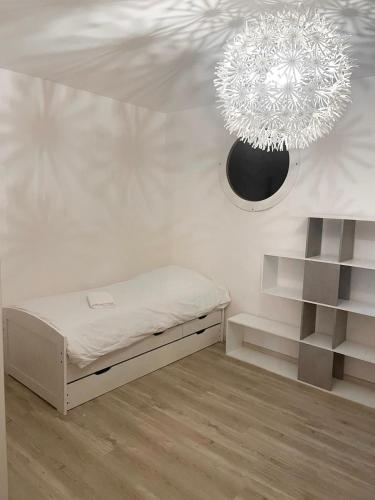 Cette chambre blanche comprend un lit et un lustre. dans l'établissement Magnifique Grand appartement Near Basel Parking privée, à Saint-Louis