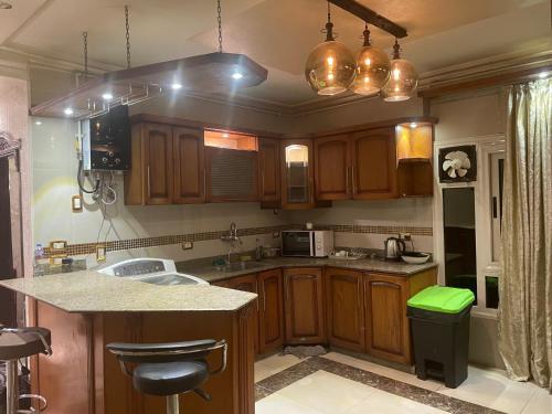 a kitchen with wooden cabinets and a green trash can at Luxury 3 bedrooms apartment for rent in a sheikh zayed compound in Kafr Abū ʼumaydah