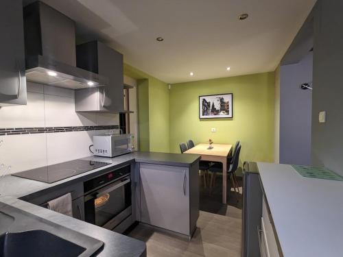 une cuisine aux murs verts et une table avec évier dans l'établissement La Petite Forge, à Krautergersheim