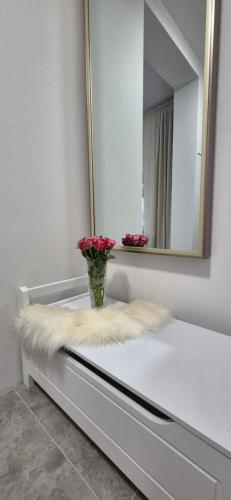 a bathroom with a mirror and a vase with flowers on a counter at Apartament Malinowe Wzgórze in Krzeszna