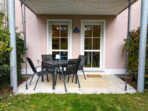 a black table and chairs in front of a pink house at Moderne Ferienwohnung in ruhiger idyllischer Lage 2 plus 2 Personen möglich in Plauen