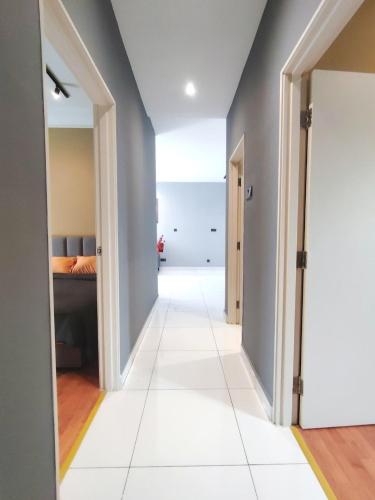 a hallway with a white tile floor and gray walls at Paradigm MarvelClassic JB Platino 3BR 10PAX in Johor Bahru