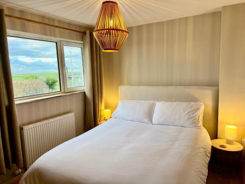 a bedroom with a white bed and a window at Channel View Heritage Coast Home in Marcross