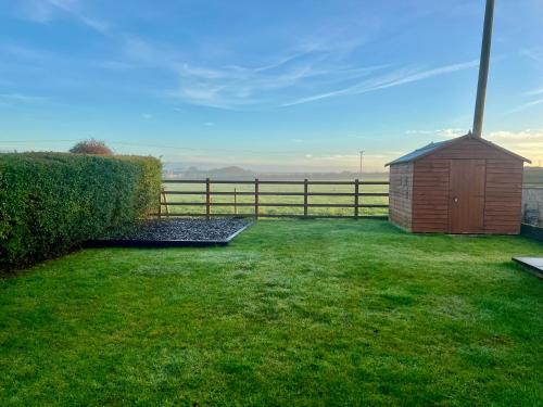 a smallshed in a grassy yard with a fence at Channel View Heritage Coast Home in Marcross