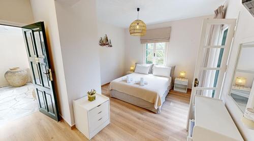 a white bedroom with a bed and a window at Andrikos Studios in Lákka