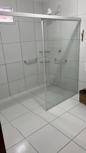 a glass shower in a bathroom with white tiles at Suítes Cantinho do Ze em Milagres in São Miguel dos Milagres