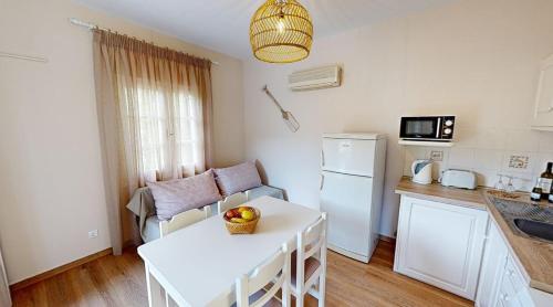 a kitchen with a white table and a white refrigerator at Andrikos Studios in Lákka