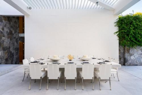 a white dining room with a long table and white chairs at Casa Brisa Luxury on The Beach in Punta Mita