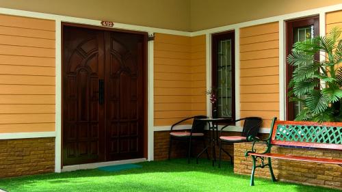 a front door of a house with a bench and a table at Malinee Villa Phuket in Bang Tao Beach