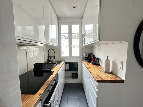une cuisine avec des armoires blanches et un comptoir en bois dans l'établissement Le Voltaire apartment - Paris Center, à Paris
