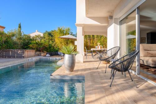 une maison dotée d'une piscine avec des chaises et une table dans l'établissement Villa avec piscine - confort et tranquillité, à Bormes-les-Mimosas