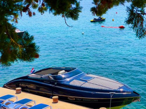 a blue boat parked on the shore of a body of water at Villa Olivija-direkt am Strand! in Stara Novalja