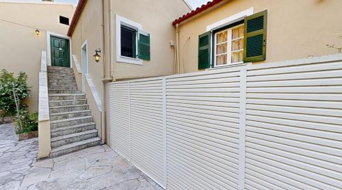 a white fence in front of a house with stairs at Andrikos Studios in Lákka