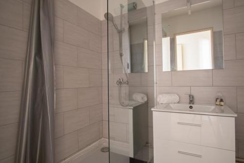 une salle de bain blanche avec une douche et un lavabo dans l'établissement Bel appartement au centre de Colmar, à Colmar