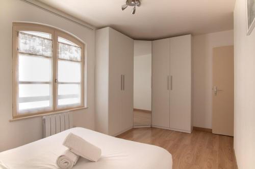 une chambre blanche avec un lit et une fenêtre dans l'établissement Bel appartement au centre de Colmar, à Colmar
