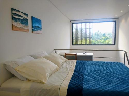 a bedroom with a bed with a blue blanket on it at Loft Novo Campeche in Florianópolis