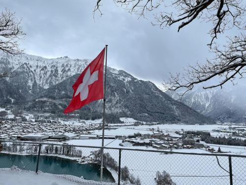 a canadian flag on a fence in front of a mountain at Aareblick 68 Charming studio with river view in Goldswil