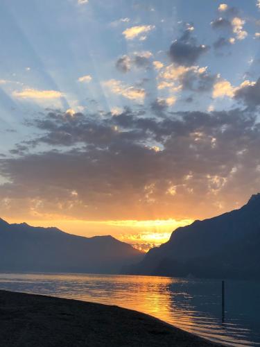 a sunset over a body of water with mountains at Aareblick 68 Charming studio with river view in Goldswil