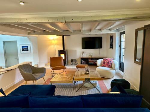 un salon avec un canapé bleu et des chaises dans l'établissement 1h10 de Paris, maison de campagne avec piscine chauffée et Jacuzzi, à Mainneville
