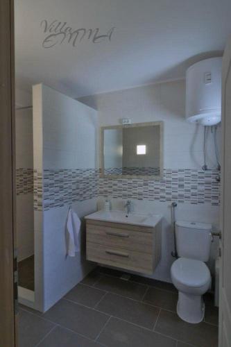 a bathroom with a white toilet and a sink at Villa Emma in Zovik