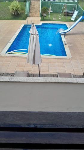 a pool with an umbrella next to a swimming pool at Recanto Azedo e Azedinhas Itu Mairinque in Itu
