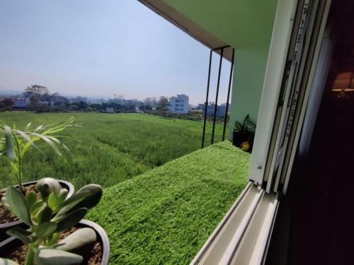 a window with a view of a green field at Zen Haven - Luxury Ganga Access & Mountain View in Rishīkesh