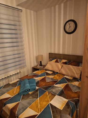 克拉古耶瓦茨Victory的卧室内的一张床铺,墙上挂着一个时钟