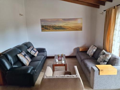 a living room with a black leather couch and a table at Habitación en Casa San Miguel, Vereda El Plan, Santa Elena in Medellín