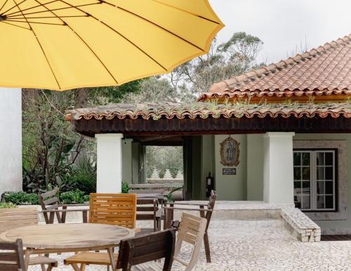 Un patio con mesas y sillas y una sombrilla amarilla. en Sintra Lagon, en Sintra