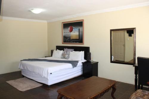 a bedroom with a bed and a table and a mirror at Bodulo Lodge in Thaba Nchu