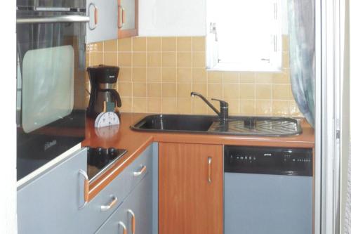 une petite cuisine avec un évier et une cuisinière dans l'établissement Appartement confortable au Cap d'Agde 55 m² avec vue mer, au Cap d'Agde