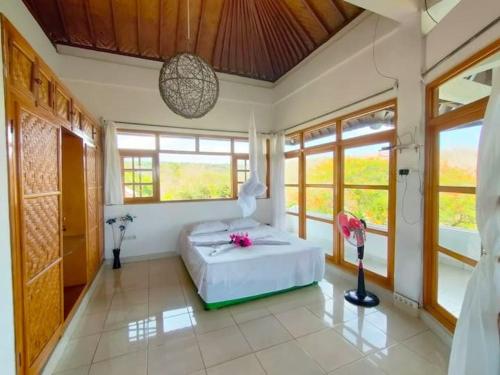 a bedroom with a bed in a room with windows at Mimpi Bungalow 3A in Kubutambahan