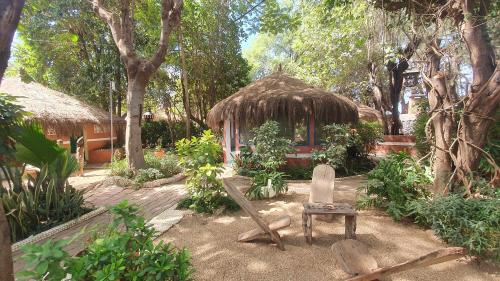 a chair and a hut in a garden with trees at LE BENTENIER Home Détente in Nianing