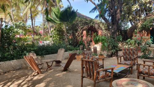 a group of chairs and tables in a garden at LE BENTENIER Home Détente in Nianing