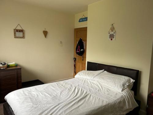 une chambre avec un lit avec des draps blancs et une porte en bois dans l'établissement Cosy 3 bedroom house to rent, à Manchester