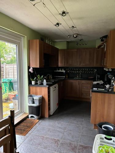 a kitchen with wooden cabinets and a white dishwasher at Cosy 3 bedroom house to rent in Manchester