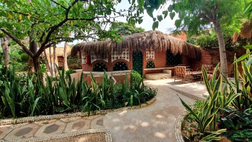 a house with a straw roof in a garden at LE BENTENIER Home Détente in Nianing